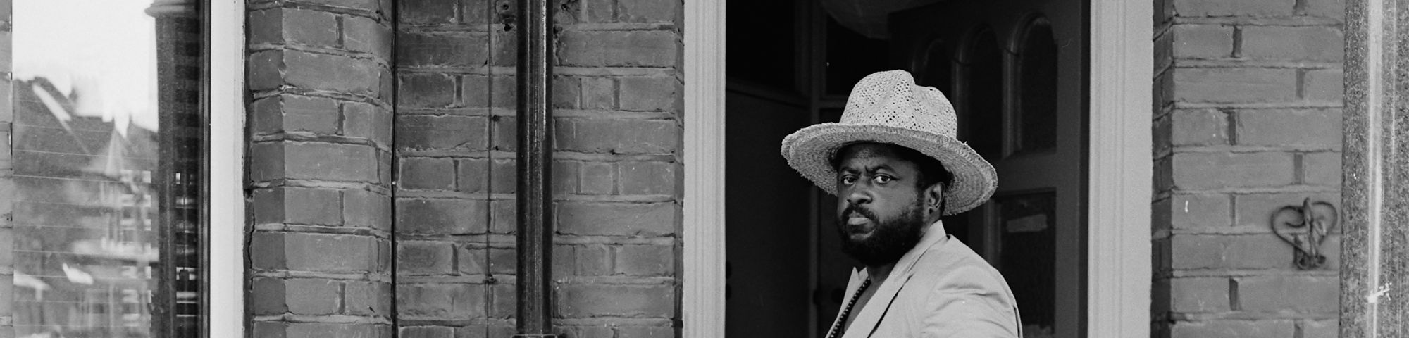 man standing on a doorstep wearing a hat