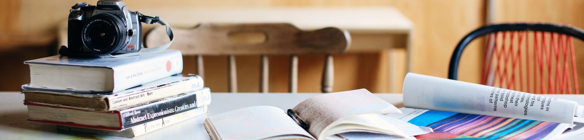 Image of a camera and a pile of books on a desk