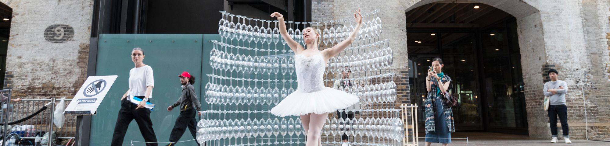 A person dancing next to lots of rows of glasses