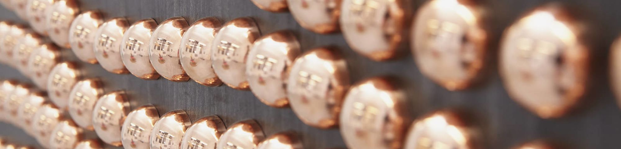 decorative image of lines of rounded copper buttons on a black wall