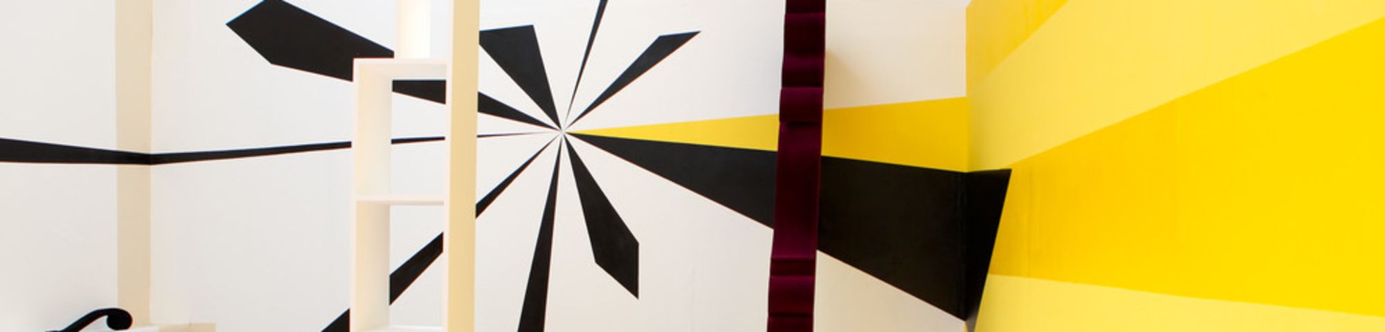 Multicoloured objects against a yellow wall and white wall