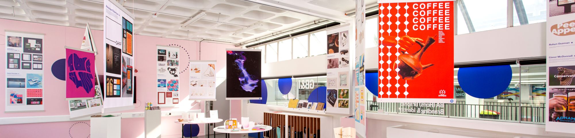 Exhibition space with student posters and work hanging and displayed around the space.