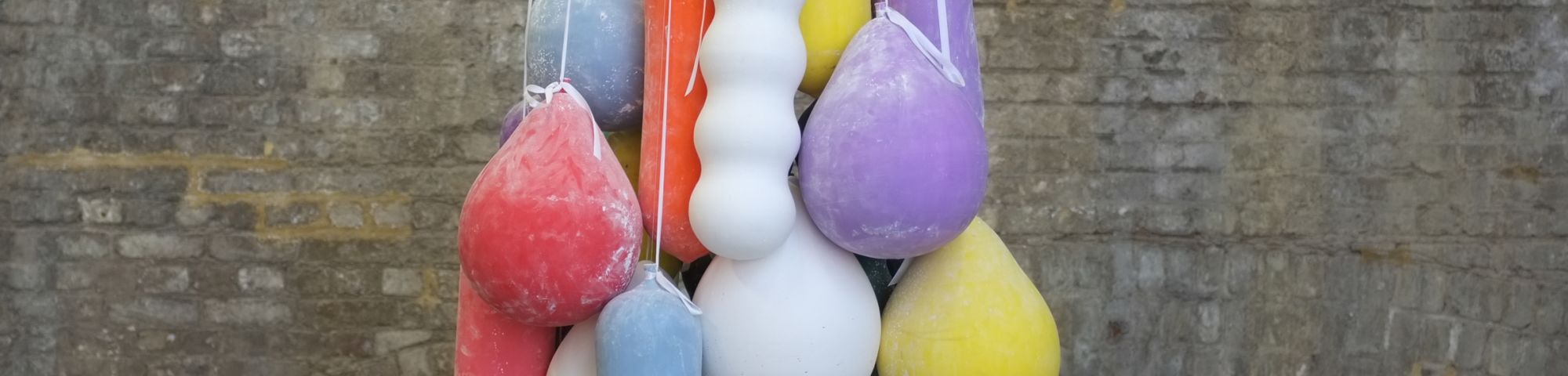 Ceramic balloons hanging in front of a brick wall