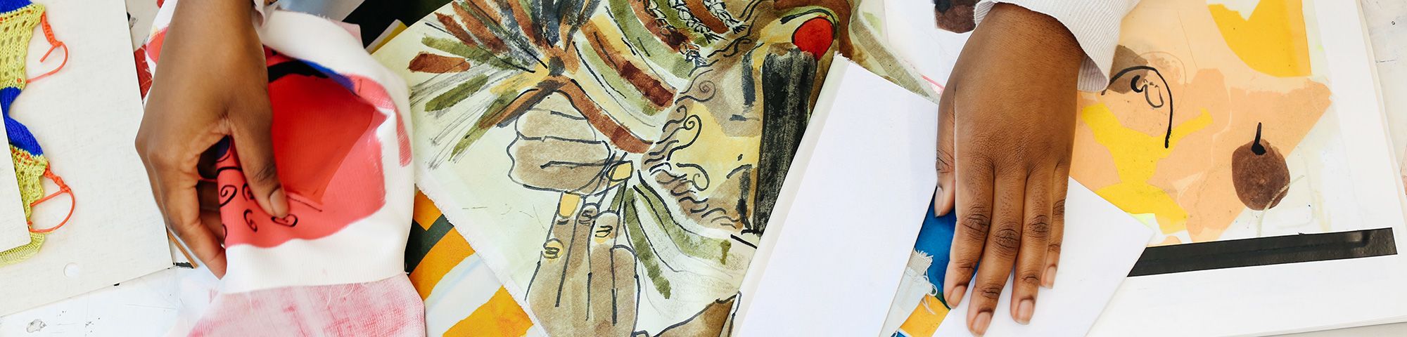 Hands across a set of colourful papers