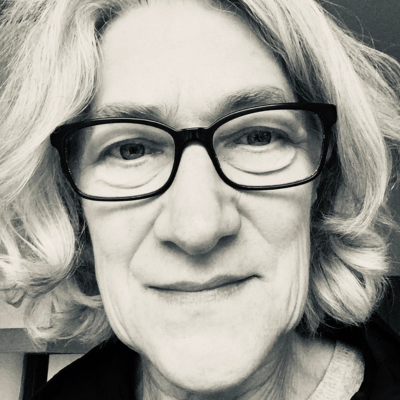 Sheila Clark, wearing black glasses and smiling at the camera