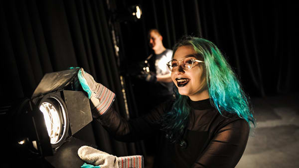 Green-haired girl operating a stage light