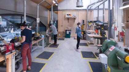People using tools and machinery inside a large workshop at Central Saint Martins