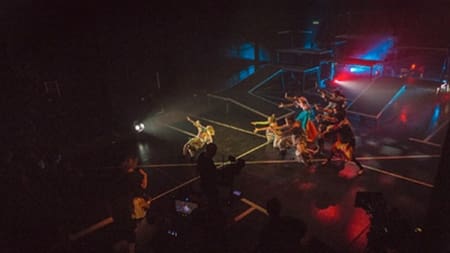 A dancers wearing bright colours performing on the stage at the Platform Theatre