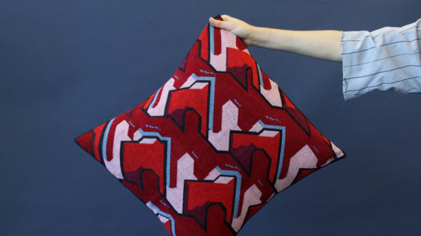 Hand holding a red patterned cushion