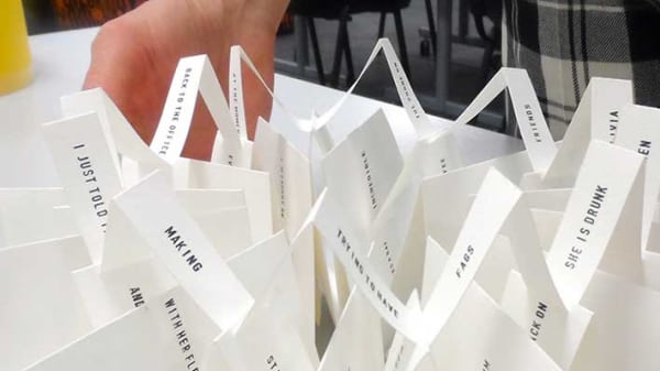 Photo of a hand next to a collection of folder papers with phrases printed on them