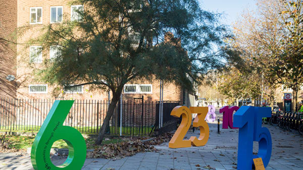 Several colourful and oversized numbers positioned near a hire bike stand.