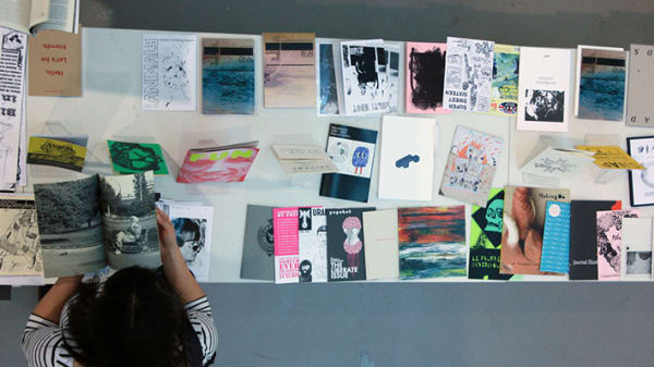 Aerial view of a woman standing over a table of papers and art work laid out