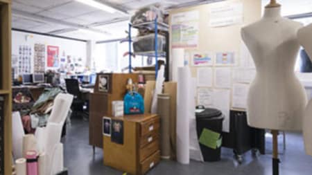 Inside the Costume Store at Central Saint martins. There are posters on a far wall and the room is filled with cupboards, rolls of posters and a mannequin.