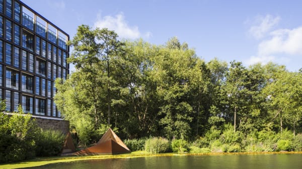 Two triangular seats among trees overlooking a canal