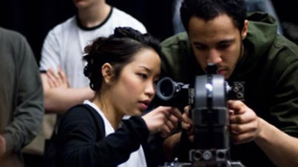 Photo of a man and a woman looking at a video camera