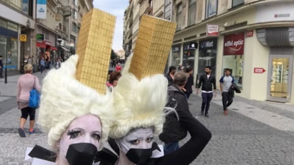 Photo of two women wearing ice cream cone costumes on their heads with black circles fixed over their mouths and black and white colours on