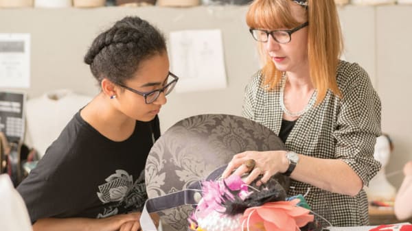 Photo of two women working on a piece of brown material