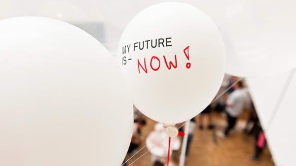 A white balloon floats with the text, my future is now, written on it.