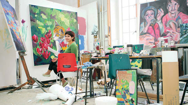 A painter in her studio looking to camera