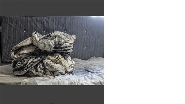 Scrunched up blue soiled sheets with a mattress behind