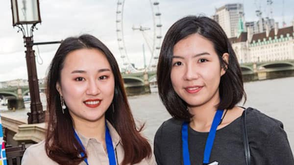 Two young women who are holding a magazine and standing in Southbank by the river Thames.