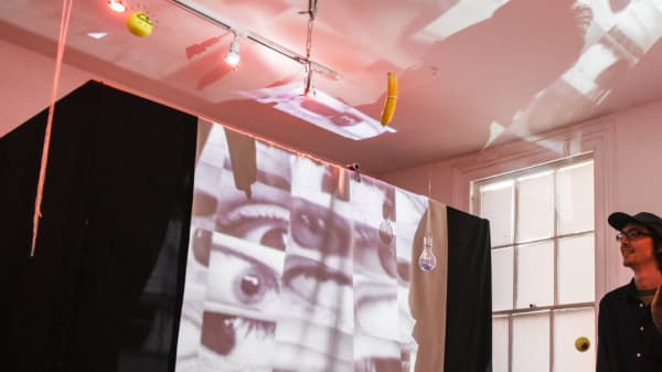 Photograph of a student interacting with a sound arts piece showing images multiple eyes projected onto a structure.
