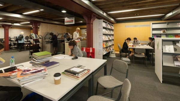 Students working at tables inside Central Saint Martins' Library