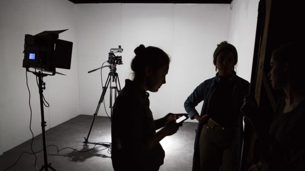 Silhouettes of students and film cameras against a white backdrop