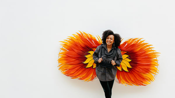 Woman standing in front of large orange and yellow flower graphic