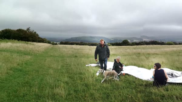 A rural landscape, people are drawing in a group in the bottom right of the photography