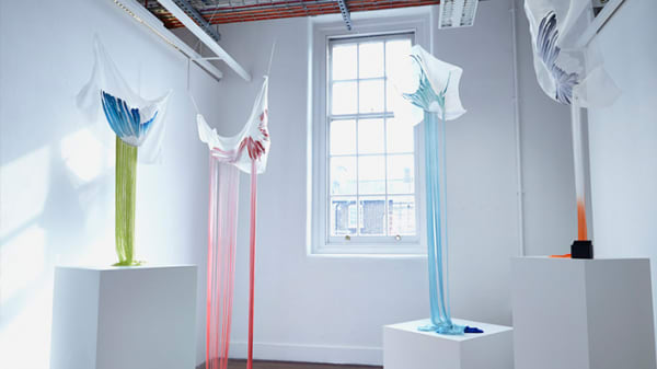Photo of a white room with a large window with pieces of material hanging down