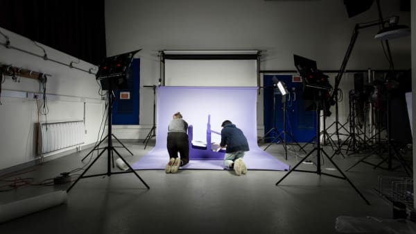 Two people in the London College of Communication photographic studio bent down on the floor