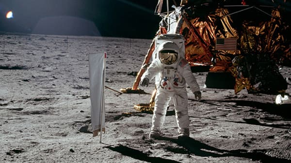 Astronaut in spacesuit stepping onto the moon. Apollo 11, moonlander in the background, with American flag. From Carl Grinter's film 'Thesis'.