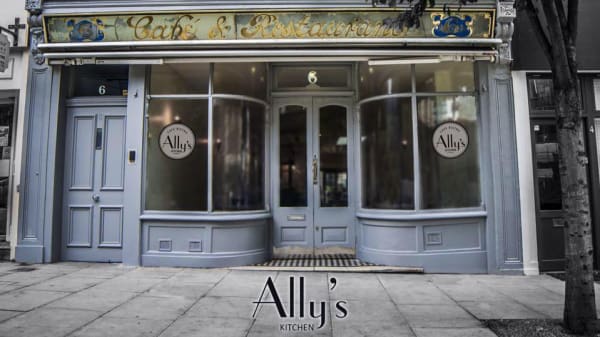 A grey building which has large windows and a sign above the door which says Cafe and Restaurant