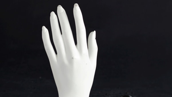 Mannequin hand peaking out of black sand