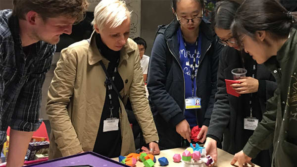 A group of postgraduate students standing around a table and interacting with a game.