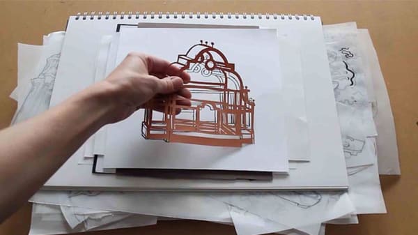 Cut outs being arranged on stacked sketchbooks