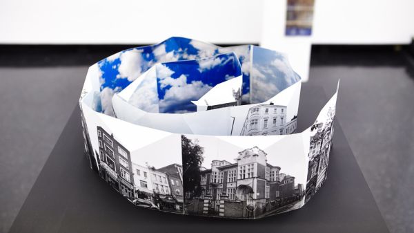Black and white photographs of a city folded into a spiral, with images of the sky 