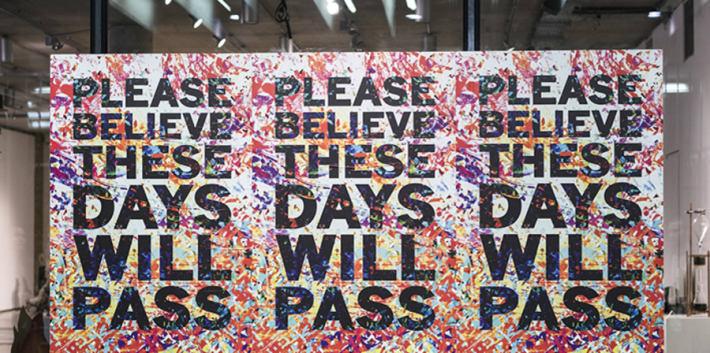 Three posters on a window which say 'These days will pass'