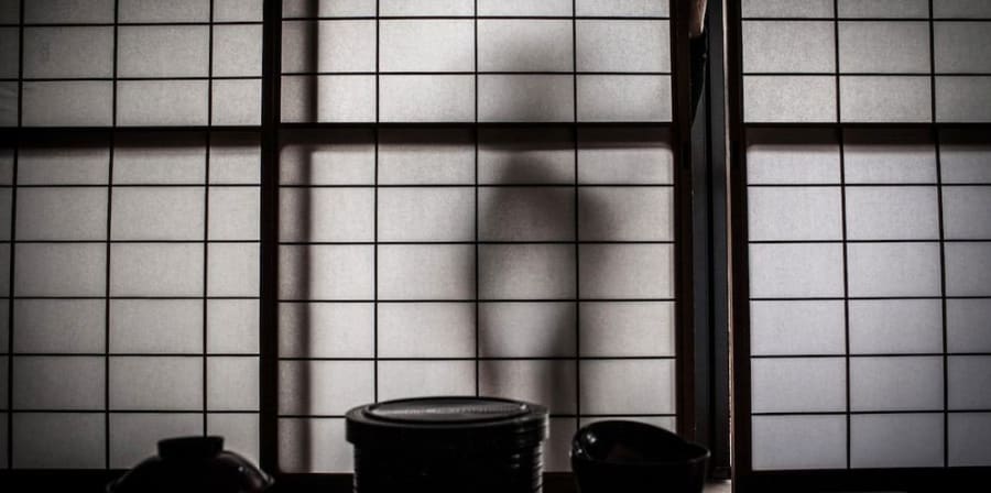 A photograph of shadows behind a Japanese screen.