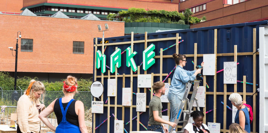 Exterior of Make space with people on ladders and view of British Library