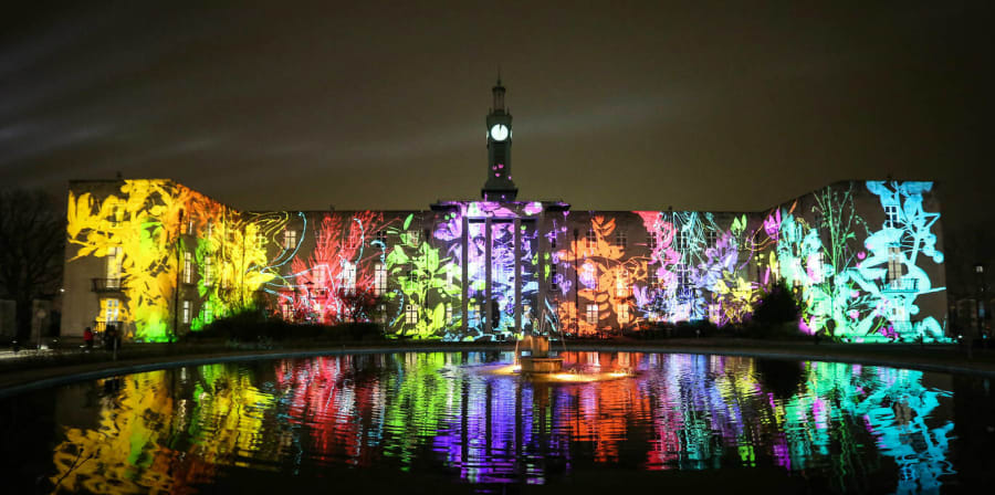 Building at nighttime with Waltham Forest bright coloured images of leaves projected on.