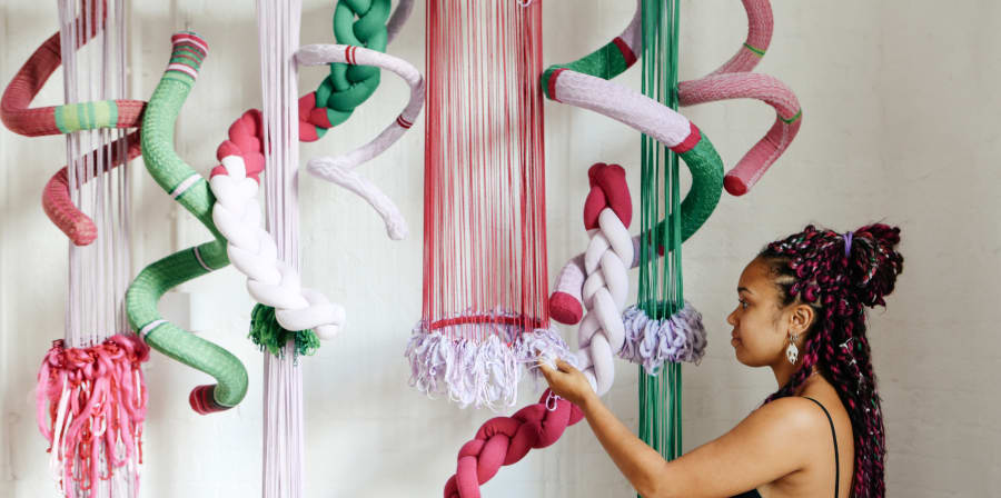 Girl interacting with a textiles installation that hangs for the ceiling