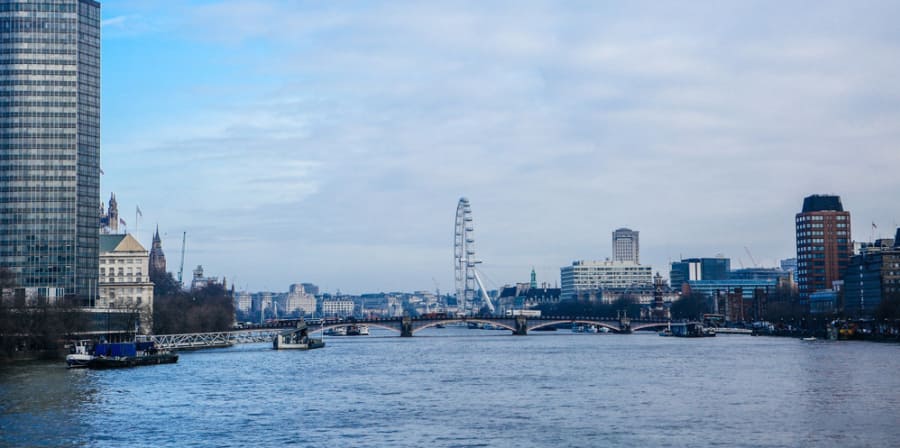 A wideshot of the River Thames and buildings of London against a blue sky