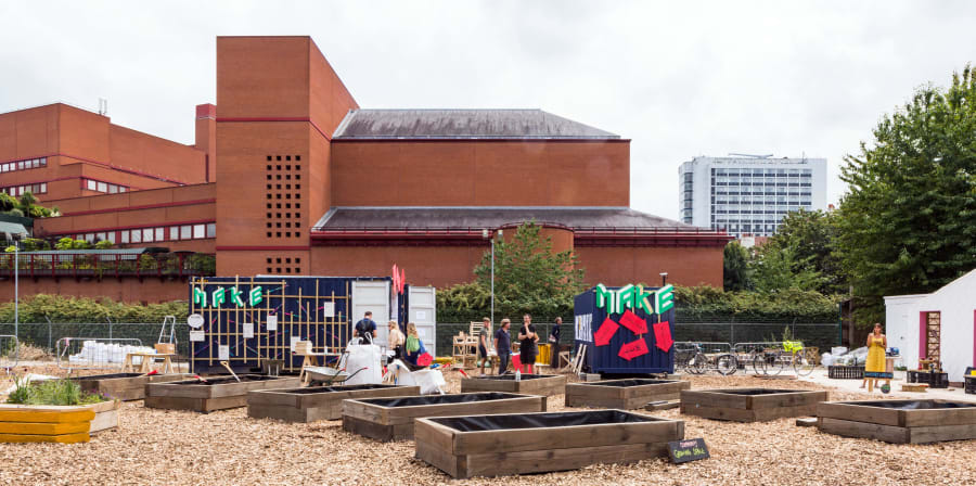 People standing with garden in front of large red building