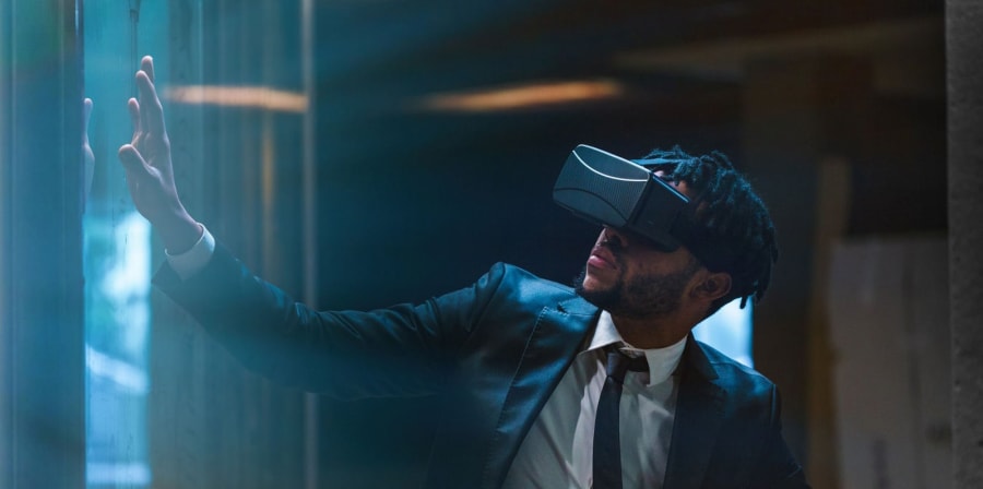 Image shows a man in a suit wearing a VR headset.