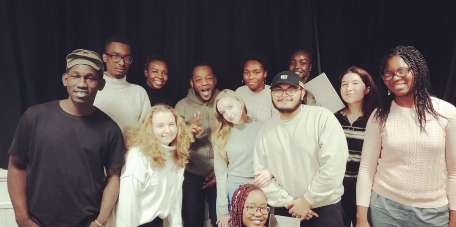 A group of students standing in front of a black curtain