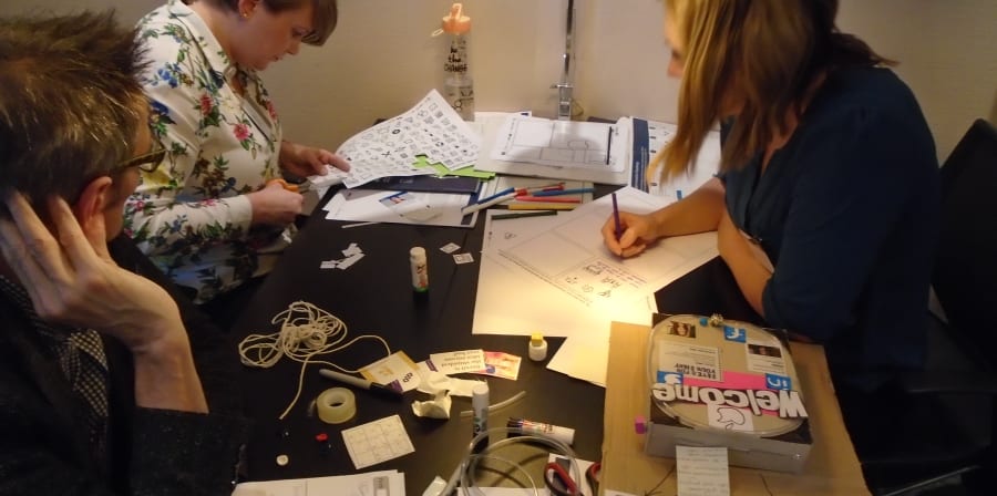 People working at a table with lots of papers and materials on the desk
