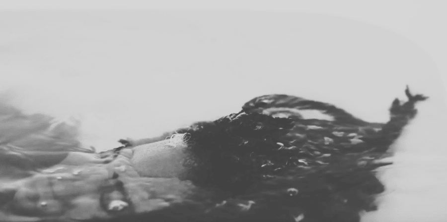 black and white image of someone under water in bath