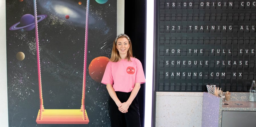 Student standing beside a display showing her work - a swing for Samsung.